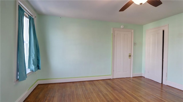 empty room featuring a ceiling fan, baseboards, and wood finished floors