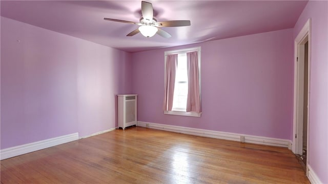 empty room featuring baseboards, wood finished floors, and a ceiling fan