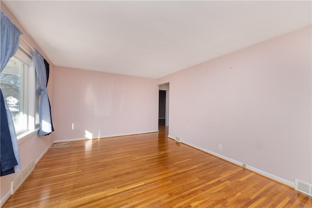 unfurnished room with light wood-style flooring, baseboards, and visible vents