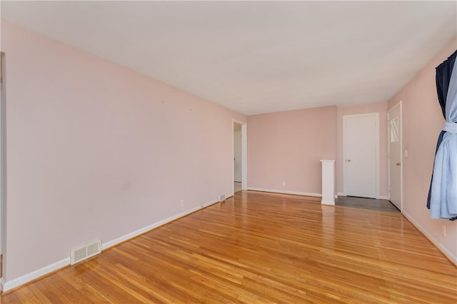 unfurnished room with light wood finished floors, visible vents, and baseboards