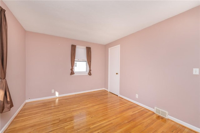 spare room featuring light wood-style floors, visible vents, and baseboards