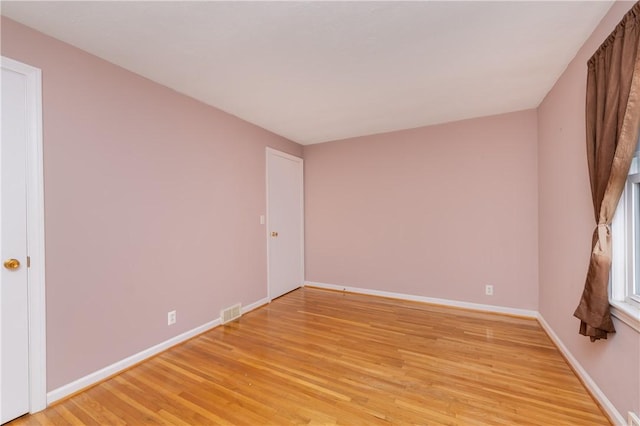 spare room with visible vents, light wood-style flooring, and baseboards