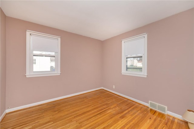 spare room with baseboards, visible vents, and light wood finished floors