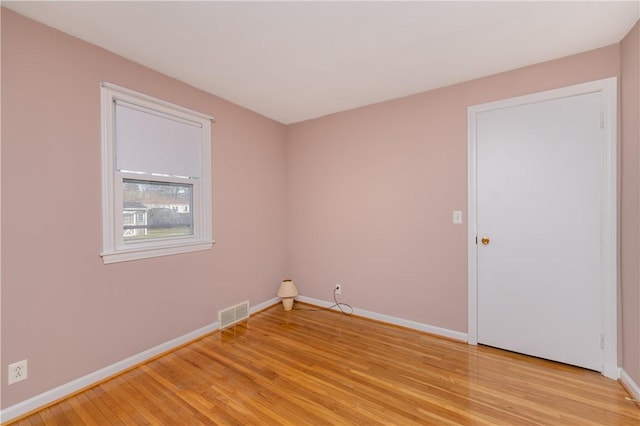 spare room with light wood-type flooring, baseboards, and visible vents