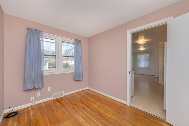 empty room with visible vents, baseboards, and light wood-style floors