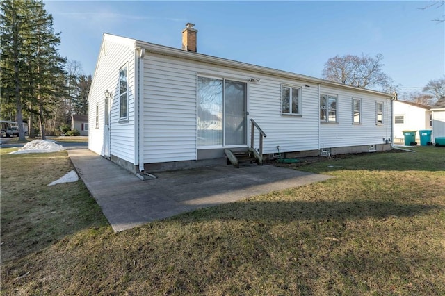 back of property with a patio, a lawn, a chimney, and entry steps