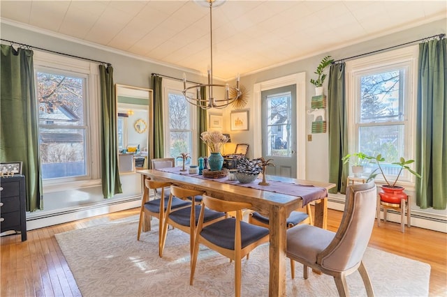 dining area featuring ornamental molding, light wood-style flooring, an inviting chandelier, and a baseboard radiator