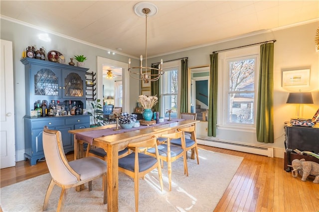 dining space with ornamental molding, light wood-type flooring, baseboards, and a baseboard radiator