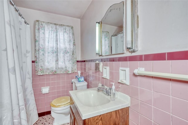 bathroom with a wainscoted wall, toilet, tile walls, and vanity