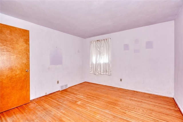 unfurnished room featuring visible vents and hardwood / wood-style floors