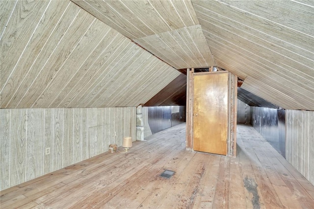 additional living space with wooden walls, visible vents, wood ceiling, lofted ceiling, and hardwood / wood-style flooring