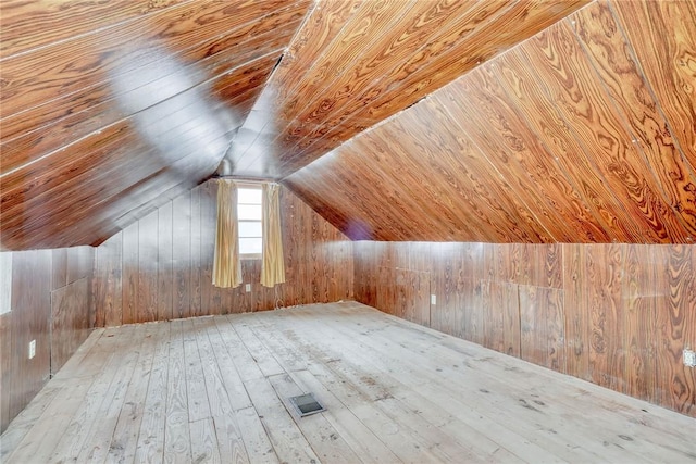 additional living space with visible vents, wood-type flooring, wooden walls, lofted ceiling, and wood ceiling