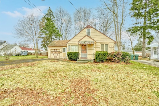 bungalow-style home with a garage and a front lawn