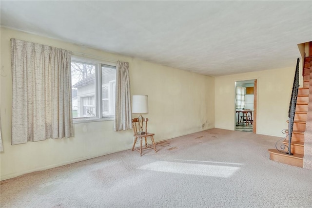 unfurnished living room with stairs and carpet