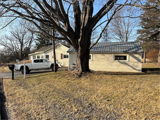 view of side of home featuring a lawn and metal roof