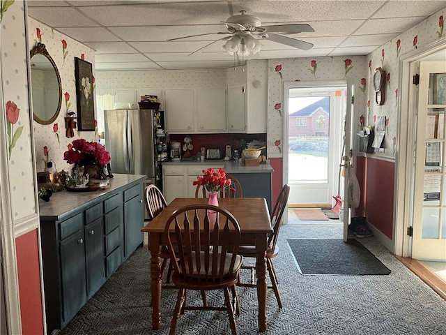 dining room with wallpapered walls, baseboards, a drop ceiling, and ceiling fan