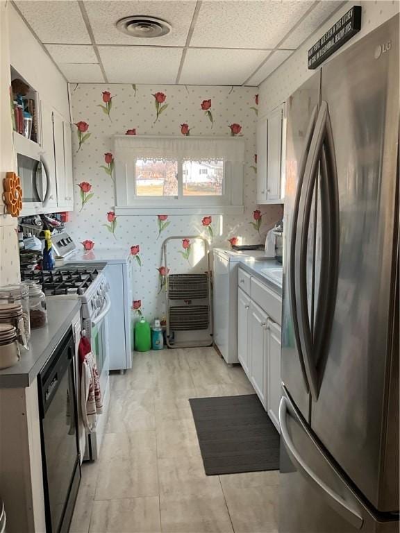 kitchen with wallpapered walls, white cabinetry, visible vents, and appliances with stainless steel finishes