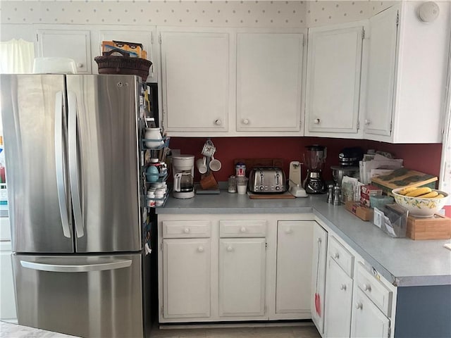 kitchen featuring light countertops, white cabinets, and freestanding refrigerator