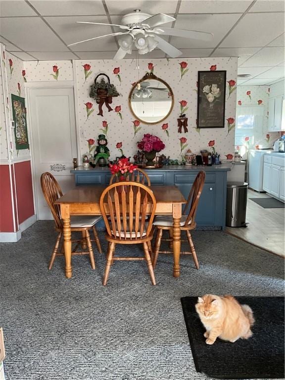 dining area featuring a drop ceiling, wallpapered walls, and a ceiling fan