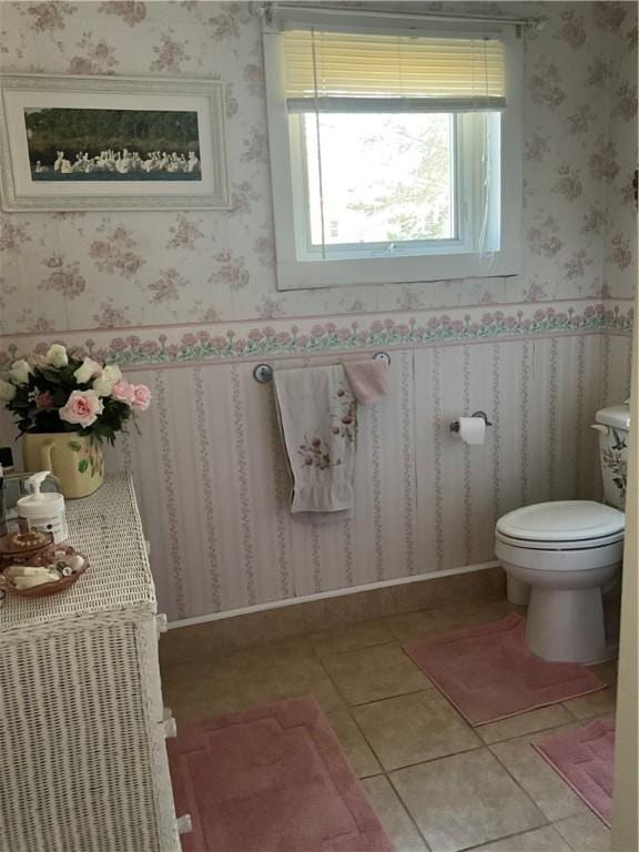 half bath featuring tile patterned floors, toilet, and wallpapered walls