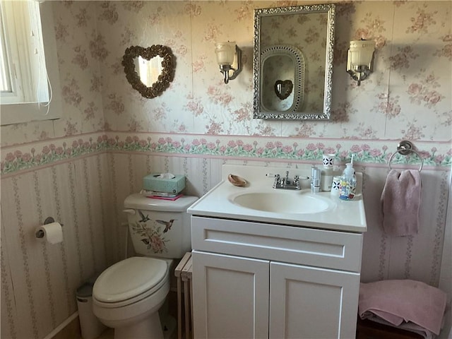 bathroom featuring toilet, vanity, and wallpapered walls