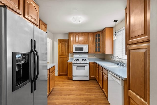 kitchen featuring white appliances, light wood-type flooring, a sink, light countertops, and brown cabinets