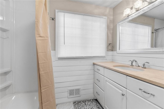 bathroom with a shower with curtain, visible vents, vanity, and wooden walls