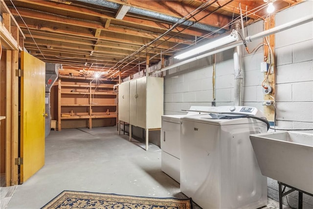 unfinished basement with a sink, separate washer and dryer, and concrete block wall