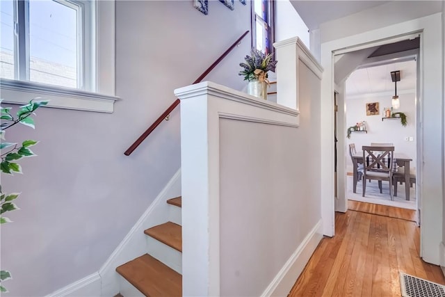 staircase with visible vents, arched walkways, and wood finished floors