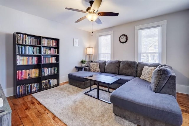 living room featuring wood finished floors, baseboards, and ceiling fan