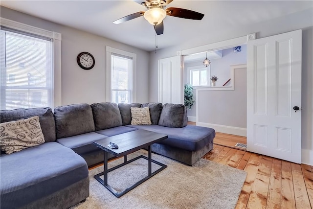 living room with visible vents, light wood-type flooring, a wealth of natural light, and baseboards