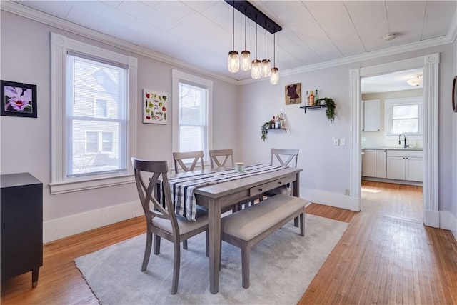 dining space featuring a wealth of natural light, light wood-style flooring, baseboards, and ornamental molding