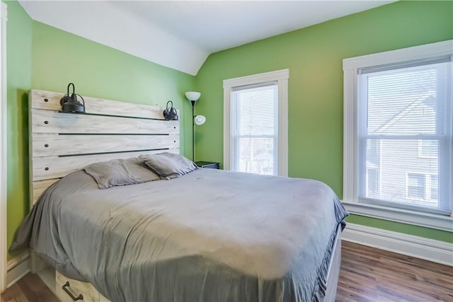 bedroom with lofted ceiling, baseboards, and wood finished floors