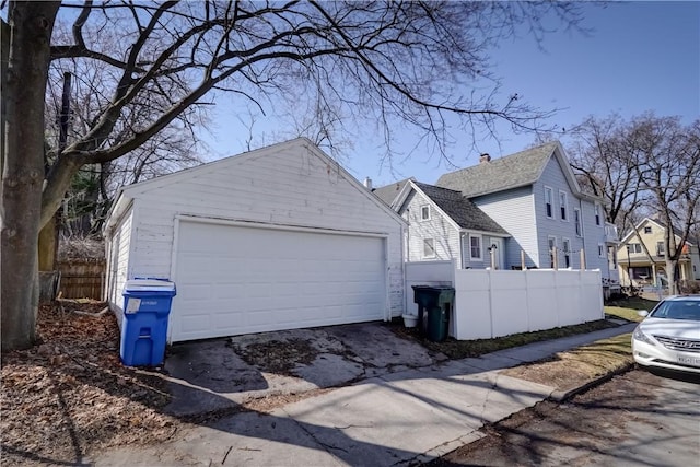 view of home's exterior featuring fence, a garage, and roof with shingles