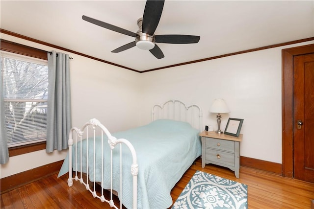 bedroom featuring a ceiling fan, wood finished floors, baseboards, and ornamental molding