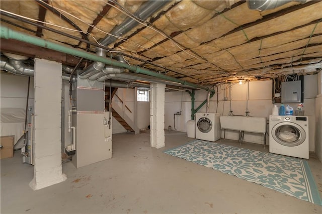 below grade area featuring heating unit, electric panel, independent washer and dryer, and a sink