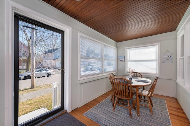 dining area featuring crown molding, light wood-style flooring, and wood ceiling