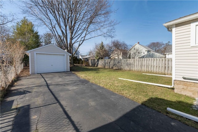 view of yard with driveway, an outdoor structure, a garage, and fence