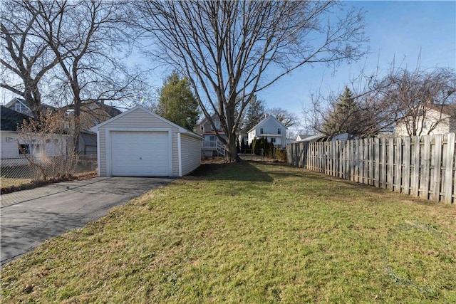 view of yard featuring an outdoor structure, fence, a garage, and driveway