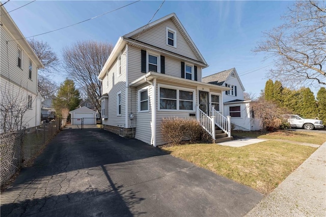 traditional style home with an outbuilding, fence, a front lawn, and driveway