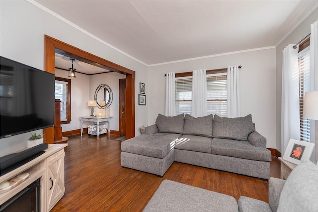 living room featuring dark wood-type flooring, crown molding, and baseboards