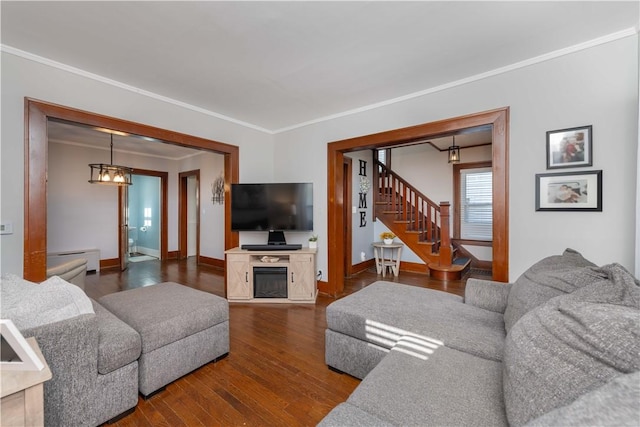 living room with stairs, dark wood-style floors, baseboards, and ornamental molding