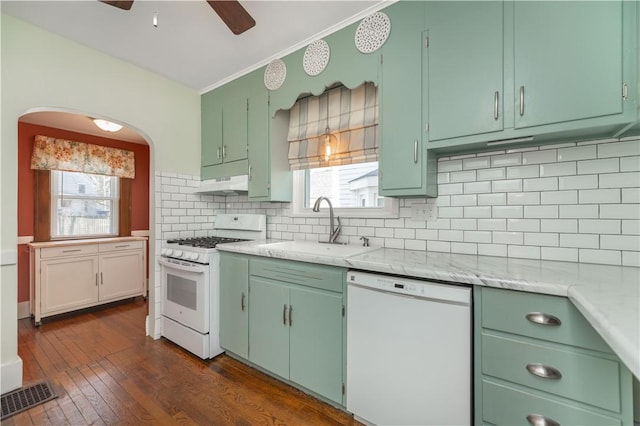 kitchen with white appliances, visible vents, a sink, decorative backsplash, and under cabinet range hood