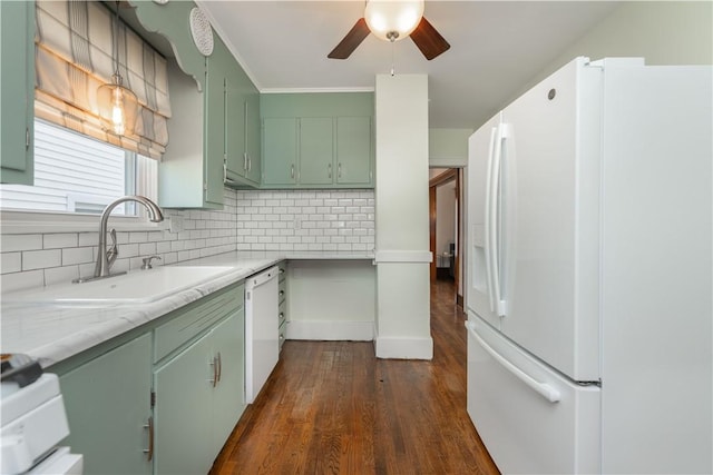 kitchen with backsplash, green cabinetry, light countertops, white appliances, and a sink