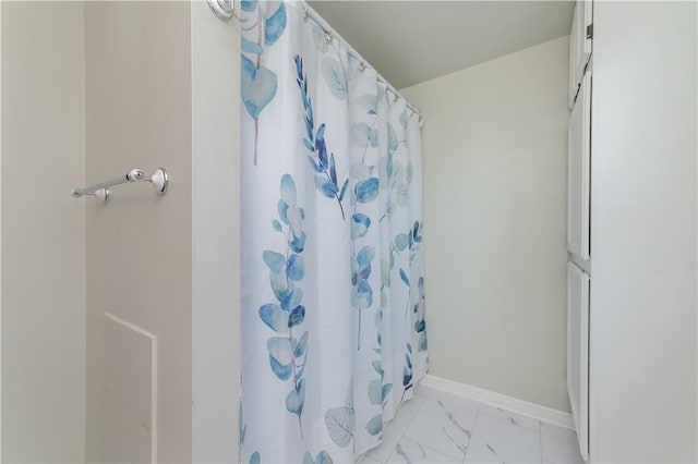 full bath with marble finish floor, curtained shower, and baseboards