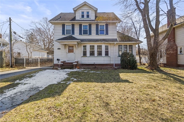 american foursquare style home featuring a shingled roof, a front lawn, and fence