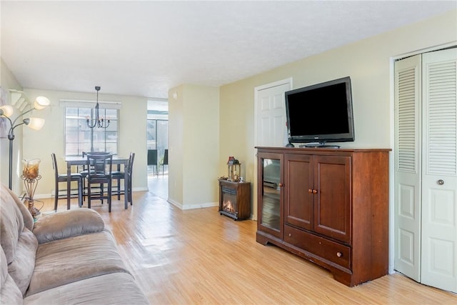 living room featuring a notable chandelier, baseboards, and light wood-type flooring