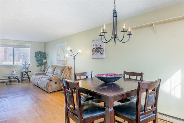 dining area with a chandelier, baseboard heating, and light wood-type flooring