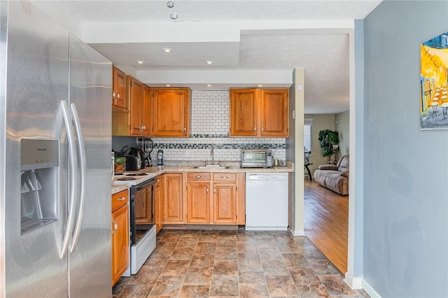 kitchen featuring a sink, electric range oven, light countertops, stainless steel refrigerator with ice dispenser, and dishwasher