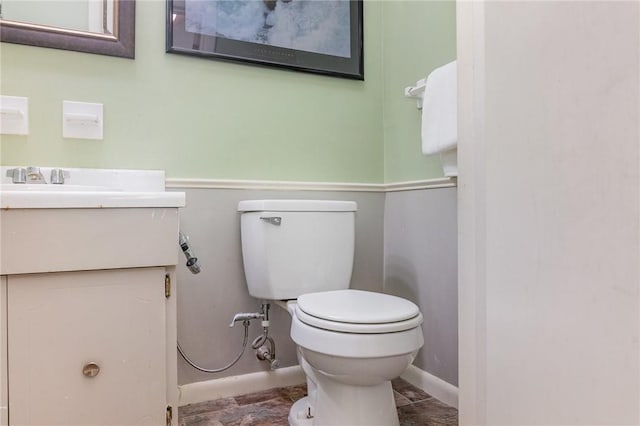 half bathroom with vanity, toilet, and baseboards